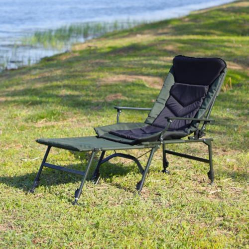 Folding camping recliner chair with footrest extended by the lake